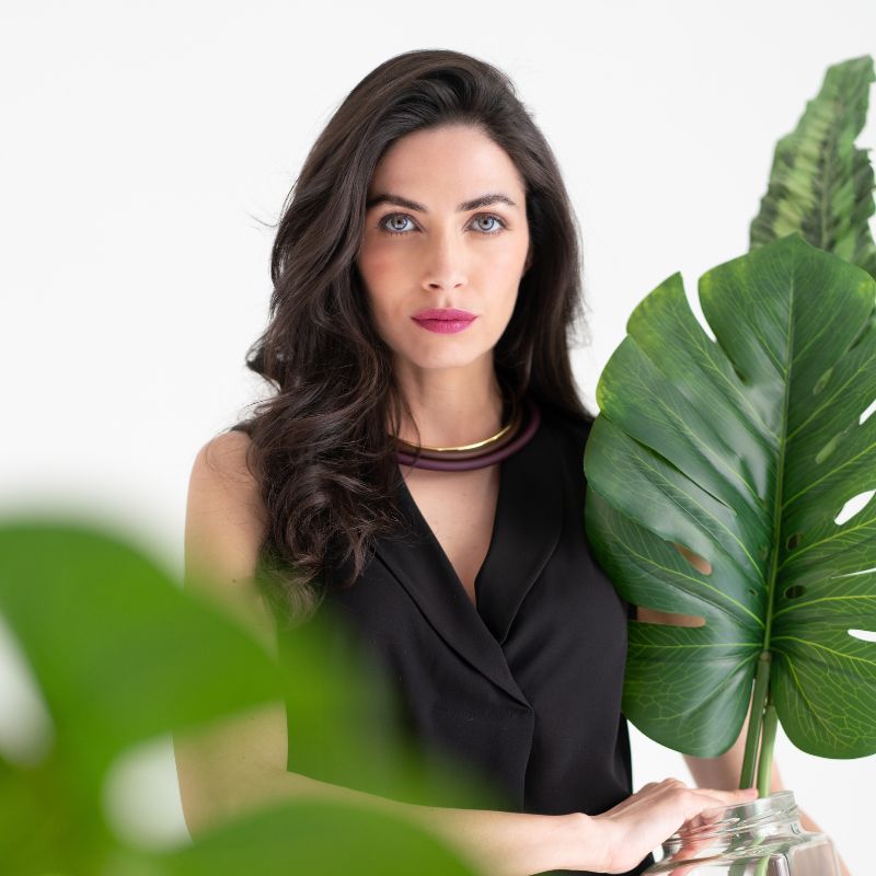 Primo piano di donna con blusa nera che tiene un vaso con foglie verdi